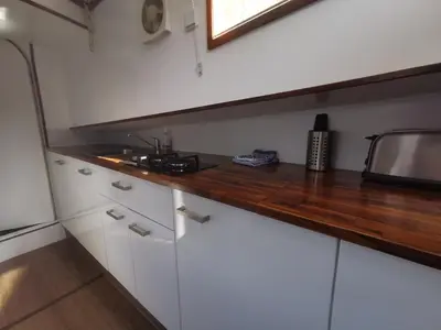 a kitchen with white cabinets and a wooden counter top at Waterloo square river vieuw houseboat in Amsterdam