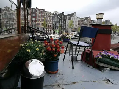 a boat with a bunch of flowers and a chair at Waterloo square river vieuw houseboat in Amsterdam