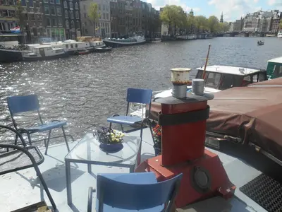 a boat with chairs and tables on the water at Waterloo square river vieuw houseboat in Amsterdam