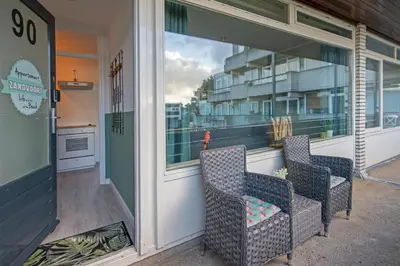 two chairs sitting on the front porch of a building at Amsterdam Beach Apartment 90 in Zandvoort