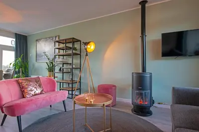 a living room with a pink couch and a fire place at Amsterdam Beach Apartment 90 in Zandvoort