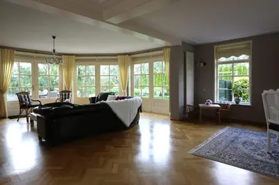 a living room with a couch and chairs and windows at Het Jaarsveldhof in Montfoort