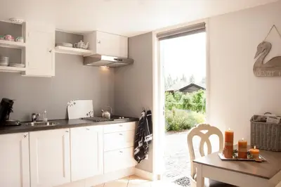 a kitchen with white cabinets and a table and a window at Het Jaarsveldhof in Montfoort