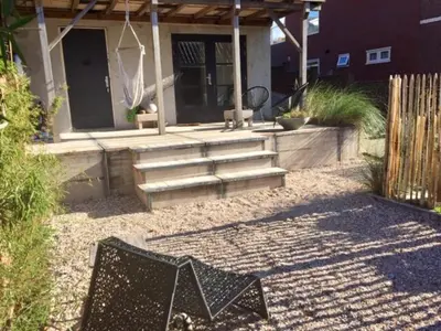 a patio with a house with stairs and a fence at ZILT sous in Noordwijk