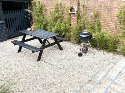 a picnic table and a grill in front of a brick wall at ZILT sous in Noordwijk