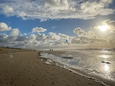 a group of people on a beach flying a kite at ZILT sous in Noordwijk