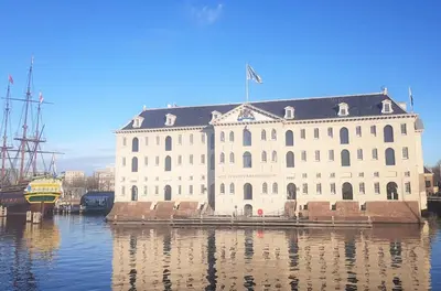 a large white building with a flag on top on the water at 23 SouS in Amsterdam