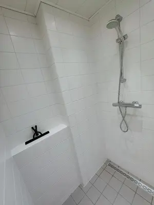 a white tiled bathroom with a shower in it at Zeehuis Appartement & Studio in Zandvoort