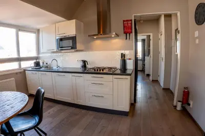 a kitchen with white cabinets and a wooden floor at Zeehuis Appartement & Studio in Zandvoort