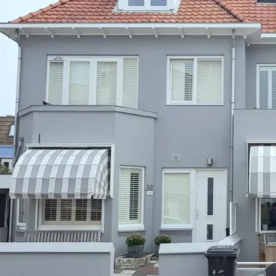 a white house with awning in front of it at Zeehuis Appartement & Studio in Zandvoort