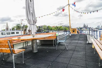 a table and chairs on a dock with a boat at Mps Holland in Amsterdam