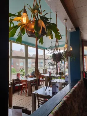 a restaurant with tables and chairs and a chandelier at Sonnevanck Wijk aan Zee in Wijk aan Zee