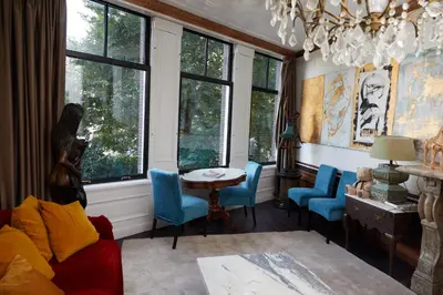 a living room with blue chairs and a table and windows at Redlightdistrict chinacitycentre partypalace in Amsterdam