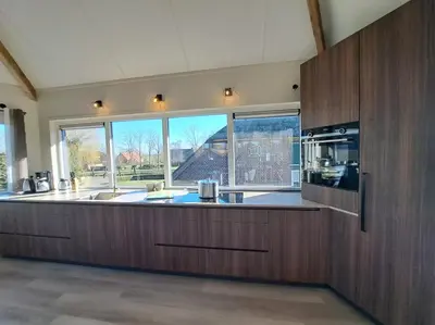a large kitchen with wooden cabinets and a large window at Apud nos Domi in Polsbroek
