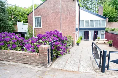 a garden with purple flowers next to a brick building at Studio Excellent 21 in Soesterberg