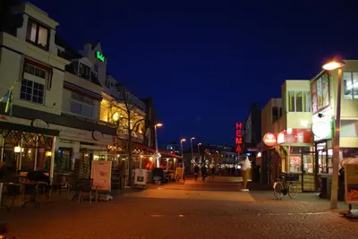 a city street at night with people walking down the street at Appartement in Zandvoort in Zandvoort