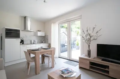 a living room with a table and a kitchen at Santvort Luxury Apartment with Private Parking in Zandvoort