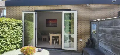 a patio with a glass door with a table in it at Santvort Luxury Apartment with Private Parking in Zandvoort