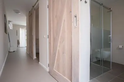 a hallway with a glass door in a bathroom at Santvort Luxury Apartment with Private Parking in Zandvoort