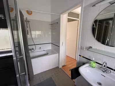 a bathroom with a sink and a tub and a mirror at Family house next to train and close to Amsterdam and Schiphol in Almere