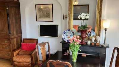 a living room with a table with flowers and a mirror at Canal View B&B Amsterdam in Amsterdam