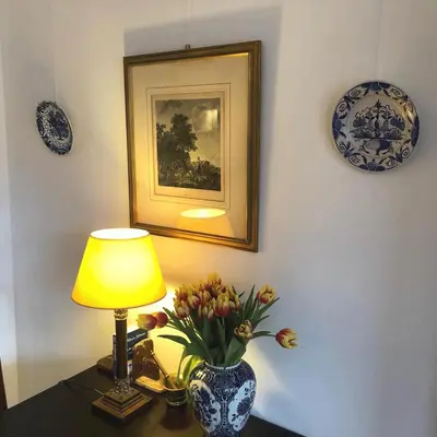 a table with a lamp and a vase with flowers on it at Canal View B&B Amsterdam in Amsterdam