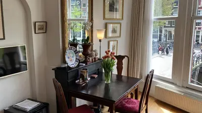 a dining room table with a vase of flowers on it at Canal View B&B Amsterdam in Amsterdam