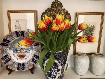 a vase with flowers on a table with pictures at Canal View B&B Amsterdam in Amsterdam