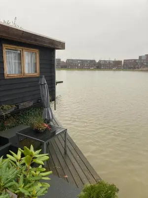 a house with a chair on a dock next to the water at Bed & Breakfast ‘t Westergouwertje in Gouda