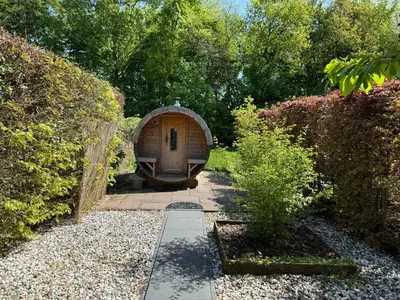 a garden with a wooden hobbit house in the middle at The Cosy Cottage for Comfort with Sauna and Hottub in Zeewolde