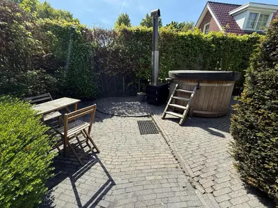 a patio with two chairs and a table and a grill at The Cosy Cottage for Comfort with Sauna and Hottub in Zeewolde