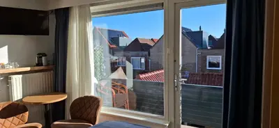 a sliding glass door with a view of a building at Bed&Breakfast aan Strand in Katwijk aan Zee