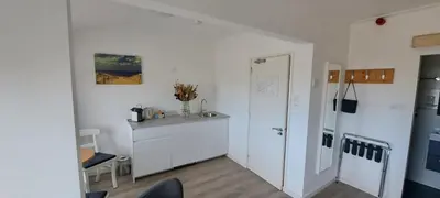 a white kitchen with a counter and a refrigerator at Bed&Breakfast aan Strand in Katwijk aan Zee
