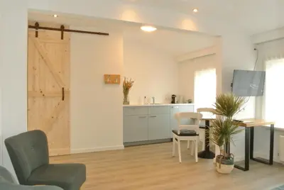 a living room with a table and chairs and a kitchen at Bed&Breakfast aan Strand in Katwijk aan Zee
