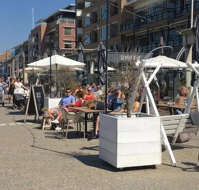 a group of people sitting at tables with umbrellas at Eb en Vloed Katwijk in Katwijk