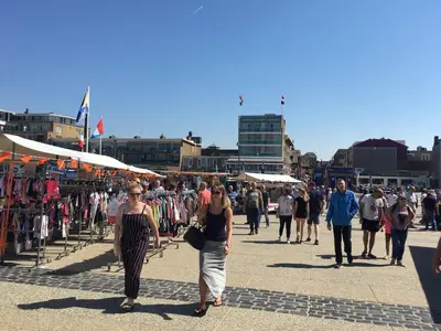 a group of people walking down a street at Eb en Vloed Katwijk in Katwijk