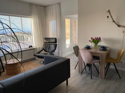 a living room with a couch and a table with chairs at Eb en Vloed Katwijk in Katwijk