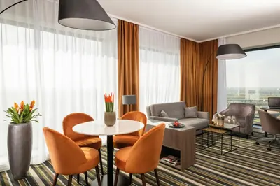 a living room with a table and chairs at Leonardo Royal Hotel Amsterdam in Amsterdam