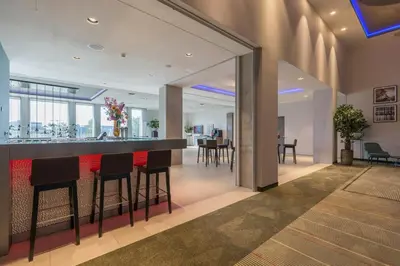 a lobby with a bar with chairs and tables at Leonardo Royal Hotel Amsterdam in Amsterdam
