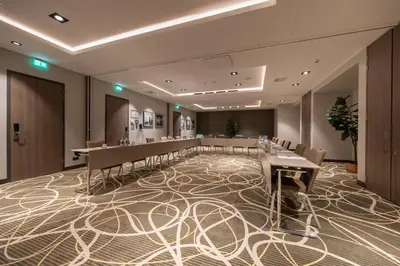 a conference room with tables and chairs on a carpet at Leonardo Royal Hotel Amsterdam in Amsterdam