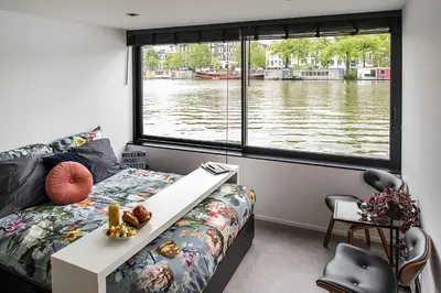 a bedroom with a view of a river from a window at Houseboat Amsterdam - Room with a view in Amsterdam