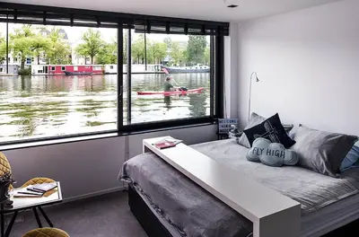 a room with a bed and a person in a kayak in the water at Houseboat Amsterdam - Room with a view in Amsterdam