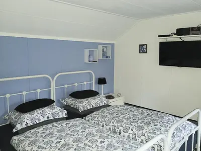 a bedroom with two beds and a flat screen tv at Prive tuinhuis B&B Elly in Sint Pancras