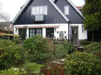 a black and white house with a porch at Prive tuinhuis B&B Elly in Sint Pancras