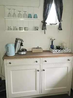 a kitchen counter with white cabinets and a window at Prive tuinhuis B&B Elly in Sint Pancras