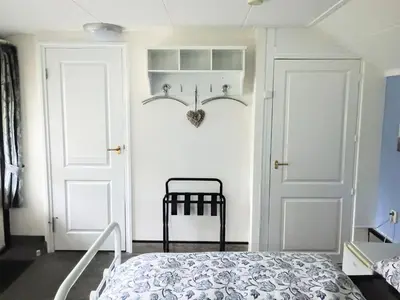 a bedroom with a bed and a white door at Prive tuinhuis B&B Elly in Sint Pancras