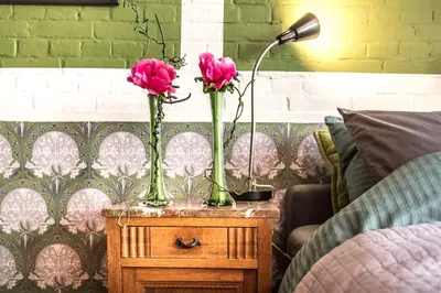two pink roses in vases on a table next to a bed at Studio Koggeschip in Amsterdam