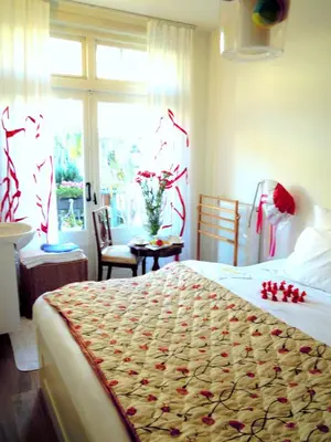 a bedroom with a bed with a flowered blanket on it at MissOrtelia B&B in Amsterdam