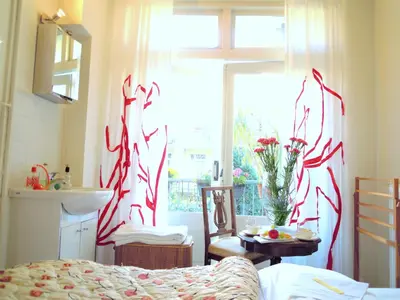a bedroom with a window with red and white curtains at MissOrtelia B&B in Amsterdam
