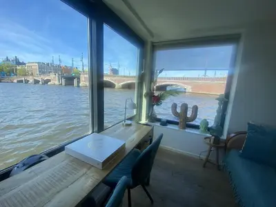 a room with a table and a view of a river at Houseboat Ark van Amstel in Amsterdam